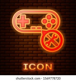 Glowing neon Gamepad with screwdriver and wrench icon isolated on brick wall background. Adjusting, service, setting, maintenance, repair, fixing.  Vector Illustration