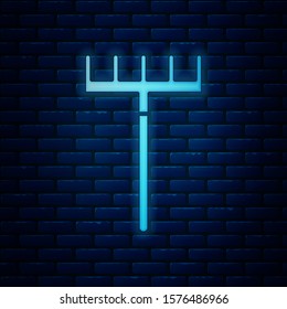 Glowing neon Garden rake icon isolated on brick wall background. Tool for horticulture, agriculture, farming. Ground cultivator. Housekeeping equipment.  Vector Illustration