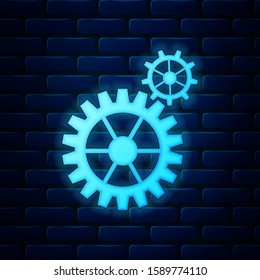 Glowing neon Gear icon isolated on brick wall background. Cogwheel gear settings sign. Cog symbol.  Vector Illustration
