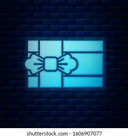 Glowing neon Gift box icon isolated on brick wall background.  Vector Illustration