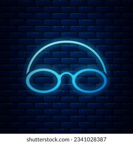 Glowing neon Glasses and cap for swimming icon isolated on brick wall background. Swimming cap and goggles. Diving underwater equipment.  Vector