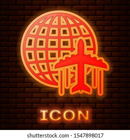 Glowing neon Globe with flying plane icon isolated on brick wall background. Airplane fly around the planet earth. Aircraft world icon.  Vector Illustration