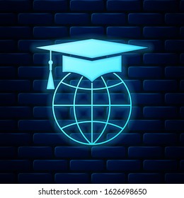 Glowing neon Graduation cap on globe icon isolated on brick wall background. World education symbol. Online learning or e-learning concept.  Vector Illustration