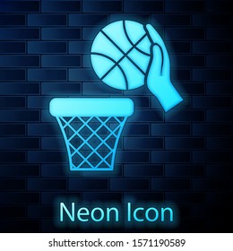 Glowing neon Hand with basketball ball and basket icon isolated on brick wall background. Ball in basketball hoop.  Vector Illustration