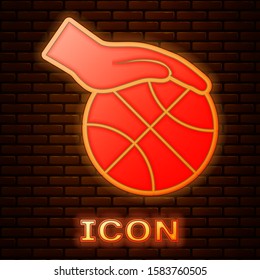 Glowing neon Hand with basketball ball icon isolated on brick wall background. Sport symbol.  Vector Illustration
