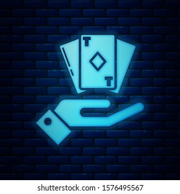 Glowing neon Hand holding deck of playing cards icon isolated on brick wall background. Casino gambling.  Vector Illustration