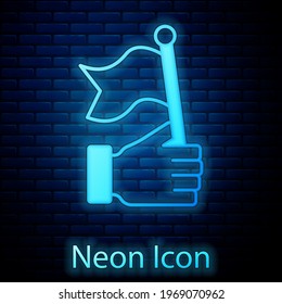 Glowing neon Hand holding flag icon isolated on brick wall background. Victory, winning and conquer adversity concept.  Vector