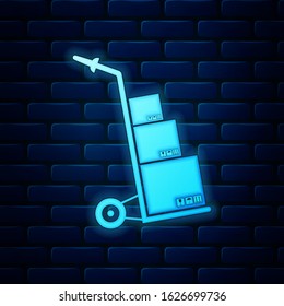 Glowing neon Hand truck and boxes icon isolated on brick wall background. Dolly symbol.  Vector Illustration