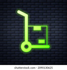 Glowing neon Hand truck and boxes icon isolated on brick wall background. Dolly symbol.  Vector