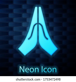 Glowing neon Hands in praying position icon isolated on brick wall background. Prayer to god with faith and hope. Vector Illustration