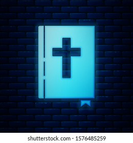 Glowing neon Holy bible book icon isolated on brick wall background.  Vector Illustration
