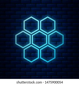 Glowing neon Honeycomb icon isolated on brick wall background. Honey cells symbol. Sweet natural food.  Vector Illustration