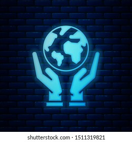Glowing neon Human hands holding Earth globe icon isolated on brick wall background. Save earth concept.  Vector Illustration