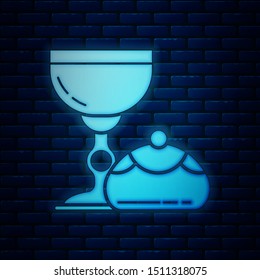 Glowing neon Jewish goblet and hanukkah sufganiyot icon isolated on brick wall background. Jewish sweet bakery. Wine cup for kiddush.  Vector Illustration