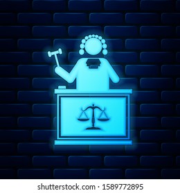 Glowing neon Judge with gavel on table icon isolated on brick wall background.  Vector Illustration