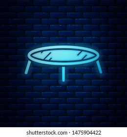 Glowing neon Jumping trampoline icon isolated on brick wall background.  Vector Illustration