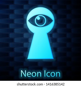 Glowing neon Keyhole with eye icon isolated on brick wall background. The eye looks into the keyhole. Keyhole eye hole. Vector Illustration