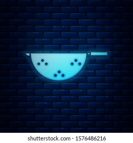 Glowing neon Kitchen colander icon isolated on brick wall background. Cooking utensil. Cutlery sign.  Vector Illustration