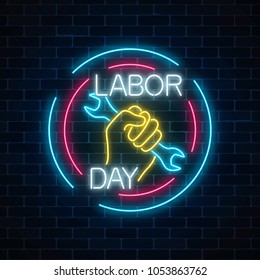 Glowing neon labor day sign in circle frames on dark brick wall background. World labor day symbol with wrench in hand. Vector illustration.