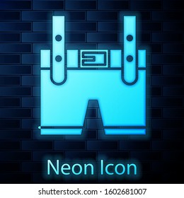 Glowing neon Lederhosen icon isolated on brick wall background. Traditional bavarian clothing. Oktoberfest outfit. Pants with suspenders. Patrick day.  Vector Illustration