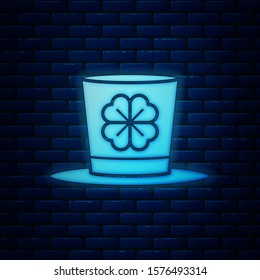 Glowing neon Leprechaun hat and four leaf clover icon isolated on brick wall background. Happy Saint Patricks day.  Vector Illustration