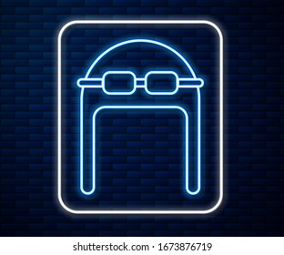 Glowing neon line Aviator hat with goggles icon isolated on brick wall background. Pilot hat.  Vector Illustration