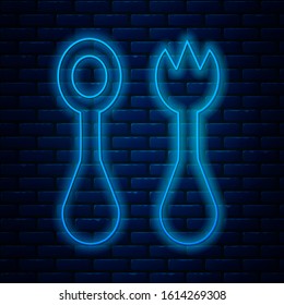 Glowing neon line Baby plastic cutlery with fork and spoon icon isolated on brick wall background. Cutlery for kid. Childrens dining items.  Vector Illustration