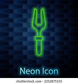 Glowing neon line Barbecue fork icon isolated on brick wall background. BBQ fork sign. Barbecue and grill tool.  Vector