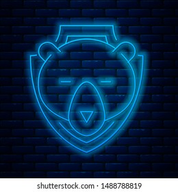 Glowing neon line Bear head on shield icon isolated on brick wall background. Hunting trophy on wall.  Vector Illustration