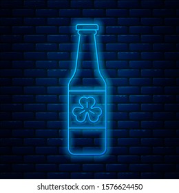 Glowing neon line Beer bottle with four leaf clover icon isolated on brick wall background. Happy Saint Patricks day.  Vector Illustration