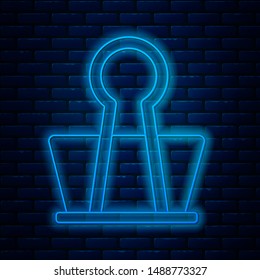 Glowing neon line Binder clip icon isolated on brick wall background. Paper clip.  Vector Illustration