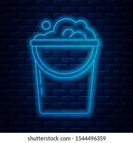 Glowing neon line Bucket with foam and bubbles icon isolated on brick wall background. Cleaning service concept.  Vector Illustration
