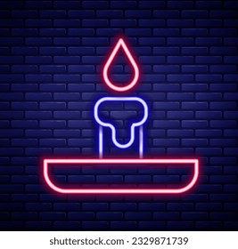 Glowing neon line Burning candle in candlestick icon isolated on brick wall background. Cylindrical candle stick with burning flame. Colorful outline concept. Vector