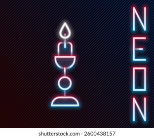 Glowing neon line Burning candle in candlestick icon isolated on black background. Old fashioned lit candle. Cylindrical candle stick with burning flame. Colorful outline concept. Vector