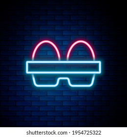 Glowing neon line Chicken egg in box icon isolated on brick wall background. Colorful outline concept. Vector