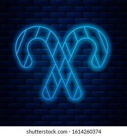 Glowing neon line Christmas candy cane with stripes icon isolated on brick wall background. Merry Christmas and Happy New Year.  Vector Illustration