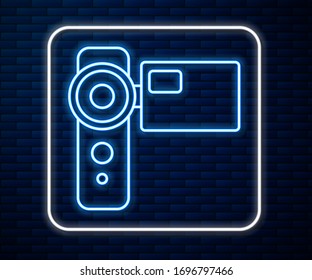 Glowing neon line Cinema camera icon isolated on brick wall background. Video camera. Movie sign. Film projector.  Vector Illustration