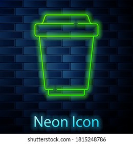 Glowing neon line Coffee cup to go icon isolated on brick wall background. Vector.