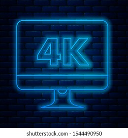 Glowing neon line Computer PC monitor display with 4k video technology icon isolated on brick wall background.  Vector Illustration