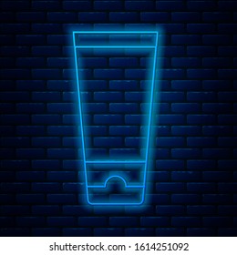 Glowing neon line Cream or lotion cosmetic tube icon isolated on brick wall background. Body care products for men.  Vector Illustration