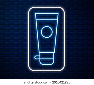 Glowing neon line Cream or lotion cosmetic tube icon isolated on brick wall background. Body care products for men.  Vector Illustration