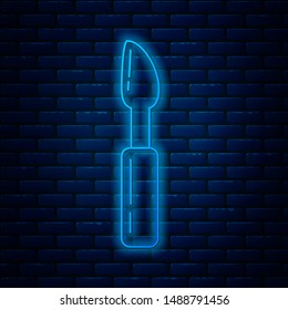 Glowing neon line Cutter tool icon isolated on brick wall background. Sewing knife with blade.  Vector Illustration