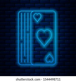 Glowing neon line Deck of playing cards icon isolated on brick wall background. Casino gambling.  Vector Illustration