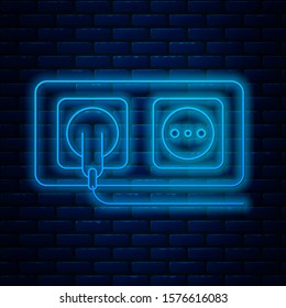 Glowing neon line Electrical outlet icon isolated on brick wall background. Power socket. Rosette symbol.  Vector Illustration