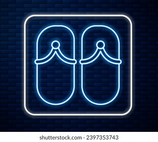 Glowing neon line Flip flops icon isolated on brick wall background. Beach slippers sign.  Vector Illustration