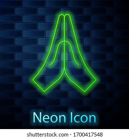 Glowing neon line Hands in praying position icon isolated on brick wall background. Prayer to god with faith and hope. Vector Illustration