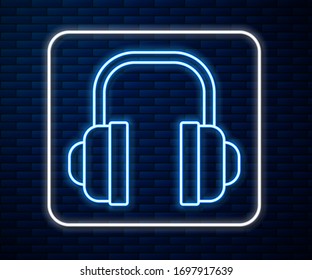 Glowing neon line Headphones icon isolated on brick wall background. Support customer service, hotline, call center, faq, maintenance.  Vector Illustration