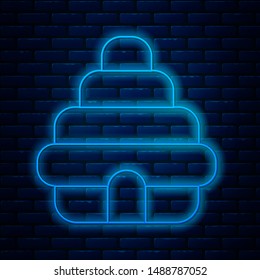 Glowing neon line Hive for bees icon isolated on brick wall background. Beehive symbol. Apiary and beekeeping. Sweet natural food.  Vector Illustration