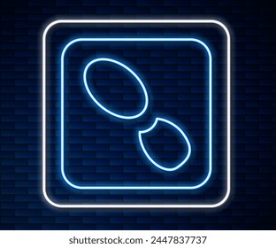 Glowing neon line Human footprints shoes icon isolated on brick wall background. Shoes sole.  Vector