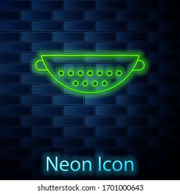 Glowing neon line Kitchen colander icon isolated on brick wall background. Cooking utensil. Cutlery sign. Vector Illustration